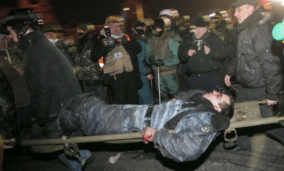 Anti-government protesters carry a wounded policemen during clashes with riot police in Kiev's Independence Square, the epicenter of the country's current unrest, Kiev, Ukraine, Wednesday, Feb. 19, 2014. Thousands of angry anti-government protesters clashed with police in a new eruption of violence following new maneuvering by Russia and the European Union to gain influence over this former Soviet republic. (AP Photo/Efrem Lukatsky)