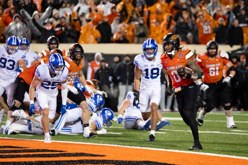 Oklahoma State running back Ollie Gordon II (0) runs past BYU defenders for a touchdown in overtime of a game, Saturday, Nov. 25, 2023, in Stillwater, Okla. | Mitch Alcala, Associated Press