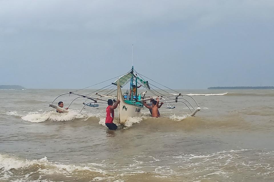 Residents help carry a wooden fishing boat into a secured area along the coast in Borongan town, Eastern Samar province, central Philippines, on December 2, 2019, as they prepare for Typhoon Kammuri. - The Philippines was braced for powerful Typhoon Kammuri as the storm churned closer, forcing evacuations and threatening plans for the Southeast Asian Games events near the capital Manila. (Photo by Alren BERONIO / AFP) (Photo by ALREN BERONIO/AFP via Getty Images)