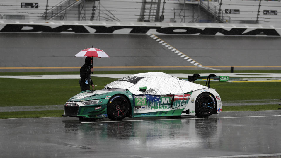 A crew member looks over the Audi R8 LMS GT3 during a red flag because of rain at the IMSA-24 hour race at Daytona International Speedway, Sunday, Jan. 27, 2019, in Daytona Beach, Fla. (AP Photo/John Raoux)