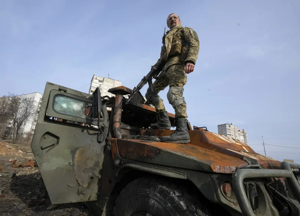 FILE - A Ukrainian soldier stands a top a destroyed Russian APC after recent battle in Kharkiv, Ukraine, on March 26, 2022. With Russia continuing to strike and encircle urban populations, from Chernihiv and Kharkiv in the north to Mariupol in the south, Ukrainian authorities said Saturday that they cannot trust statements from the Russian military Friday suggesting that the Kremlin planned to concentrate its remaining strength on wresting the entirety of Ukraine's eastern Donbas region from Ukrainian control. (AP Photo/Efrem Lukatsky)