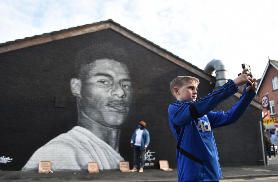 MANCHESTER, ENGLAND - NOVEMBER 07: A boy  takes a photo of a Mural of Manchester United footballer Marcus Rashford, created by local street artist Akse, after the footballer received an MBE for his work campaigning for the government to provide meals to impoverished children on November 07, 2020 in Manchester, England. (Photo by Nathan Stirk/Getty Images)