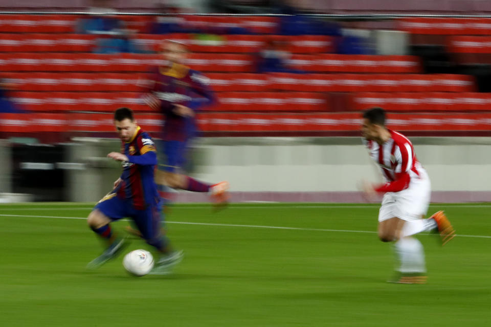 In this photo taken with slow shutter speed, Barcelona's Lionel Messi, left, runs with the ball during the Spanish La Liga soccer match between FC Barcelona and Athletic Bilbao at the Camp Nou stadium in Barcelona, Spain, Sunday, Jan. 31, 2021. (AP Photo/Joan Monfort)