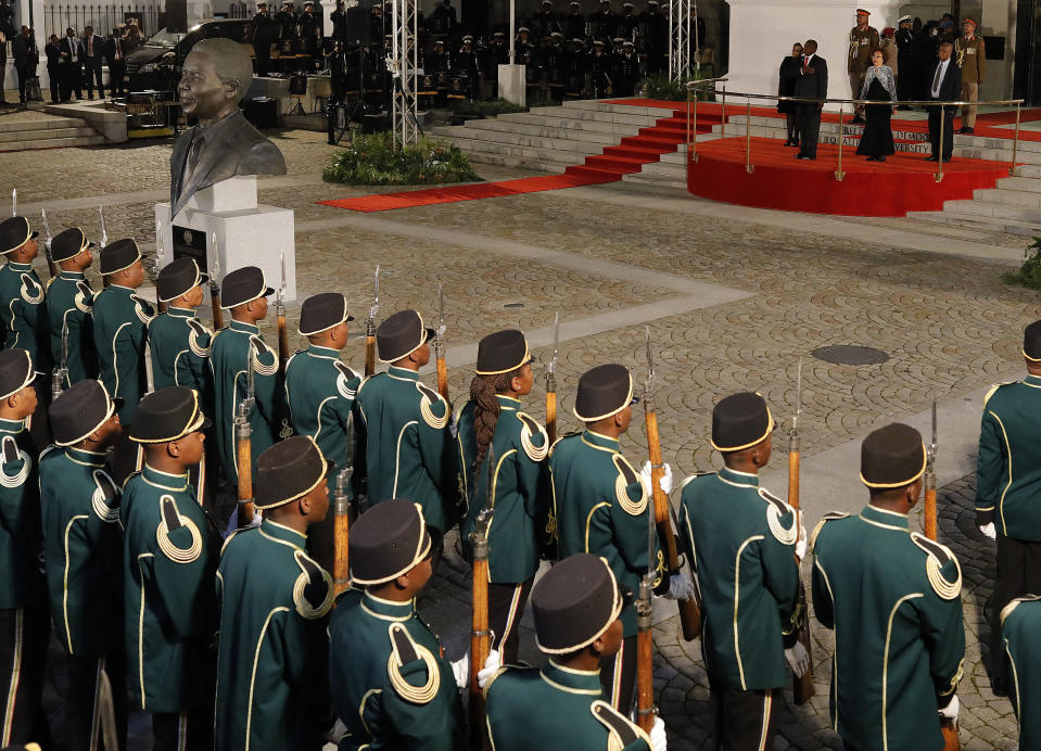 On the podium back right, President Cyril Ramaphosa, background front left, and his wife, Tshepo Motsepe, centre, stand to attention for the national salute at the opening of the sixth parliament in Cape Town, South Africa, Thursday, June 20, 2019. (Kim Ludbrook/Pool Photo via AP)