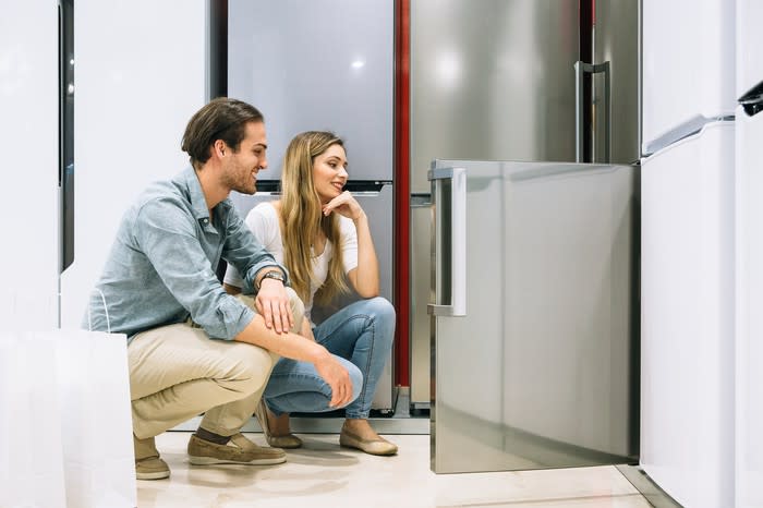 A man and a woman examining a refrigerator in a store