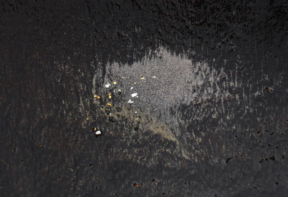 In this Jan. 19, 2017, photo, a local prospector displays flecks gold in his pan found in the Klong Thong, or "Golden Canal" in Prachuap Khiri Khan province, southern Thailand. The canal, expanded by devastating flash floods, has been washing up gold for villagers whose businesses have been swept away. (AP Photo/Sakchai Lalit)