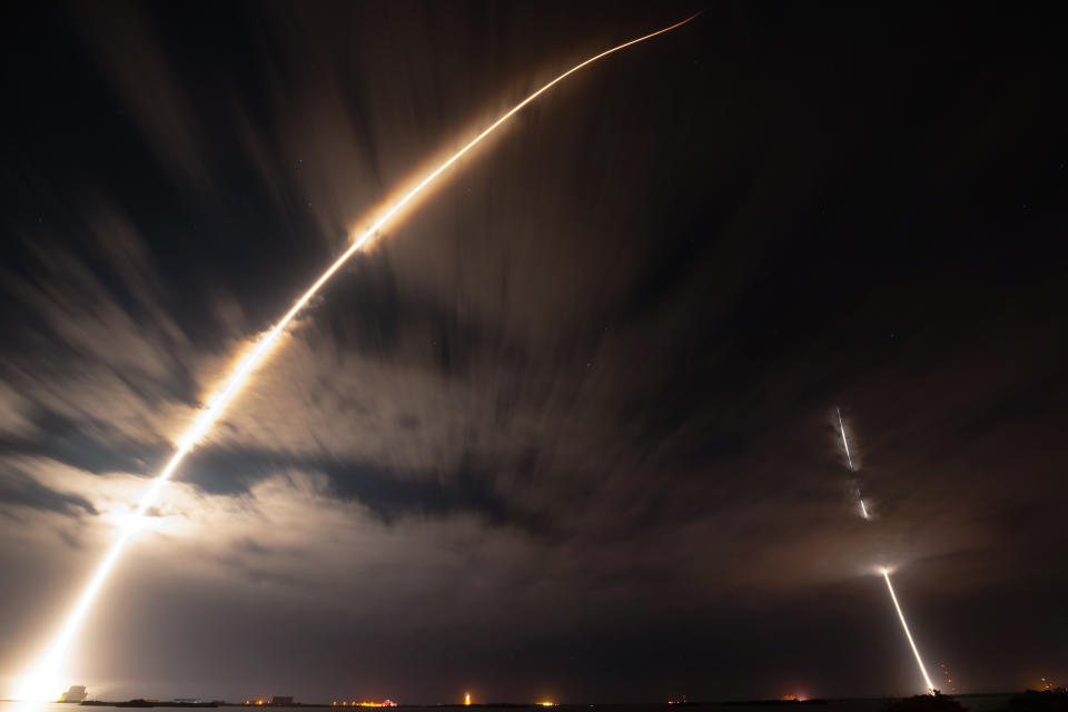 a rocket launches at night, leaving a bright plume of fire in its wake