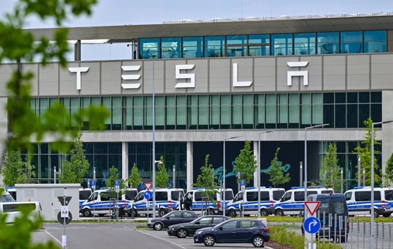 Several police vehicles are parked in front of the main entrance to the Tesla factory for safety reasons. After violent clashes at the Tesla factory site in Gruenheide near Berlin, the police are preparing for further demonstrations on Saturday. Patrick Pleul/dpa