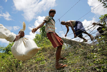 Rohingya people pass their belongings over the Bangladesh-Myanmar border fence as they try to enter Bangladesh in Cox’s Bazar, Bangladesh, August 27, 2017. REUTERS/Mohammad Ponir Hossain