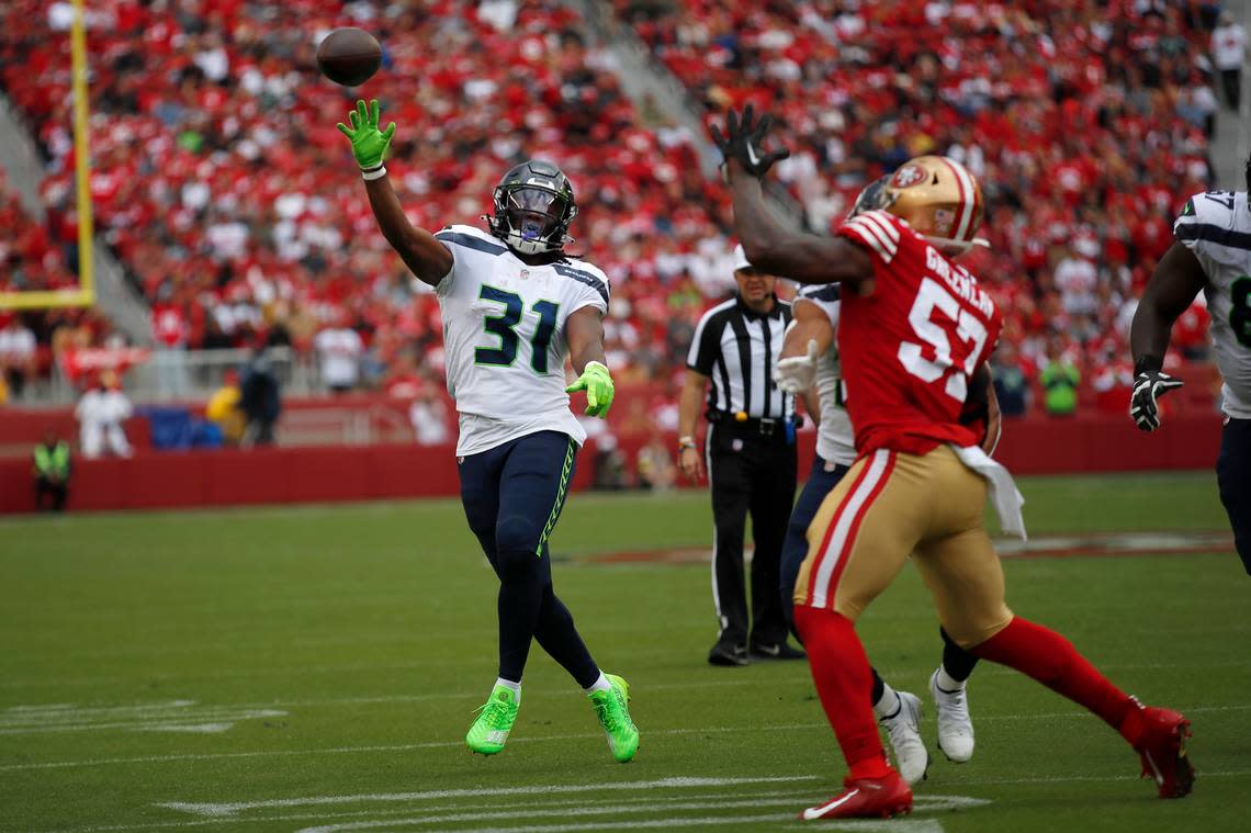 Seattle Seahawks running back DeeJay Dallas (31) throws a pass that was intercepted by San Francisco 49ers cornerback Charvarius Ward as linebacker Dre Greenlaw (57) applies pressure during the first half of an NFL football game in Santa Clara, Calif., Sunday, Sept. 18, 2022. (AP Photo/Josie Lepe)