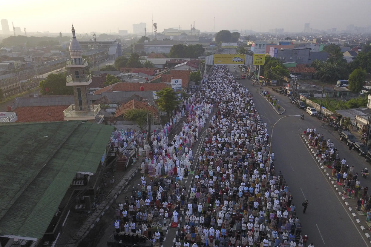 In this photo taken using a drone, Muslims perform Eid al-Fitr prayers marking the end of the holy fasting month of Ramadan on a street in Bekasi, West Java, Indonesia, Monday, May 2, 2022. (AP Photo/Achmad Ibrahim)