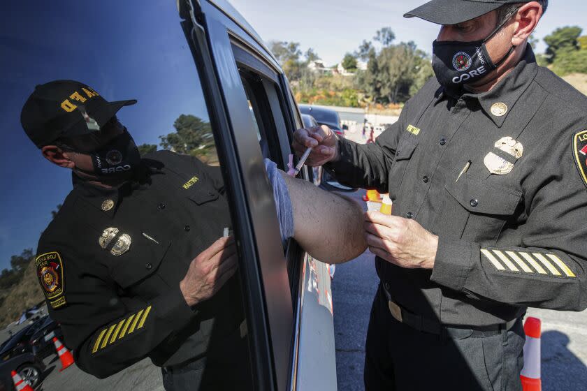 Los Angeles, CA - January 15: Los Angeles Fire Assistant Fire Chief Ellsworth Fortman administers as COVID-19 vaccine as mass-vaccination of healthcare workers starts at Dodger Stadium on Friday, Jan. 15, 2021 in Los Angeles, CA. (Irfan Khan / Los Angeles Times)