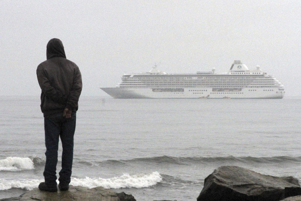 FILE - A man stands on the shore of the Bering Sea to watch the luxury cruise ship Crystal Serenity anchored just outside Nome, Alaska, because it was too big to dock at the Port of Nome, Aug. 21, 2016. Shipping lanes that were once clogged with ice for much of the year along Alaska's western and northern coasts have relented thanks to global warming, and the nation's first deep water Arctic port should be operational in Nome by the end of the decade. (AP Photo/Mark Thiessen, File)