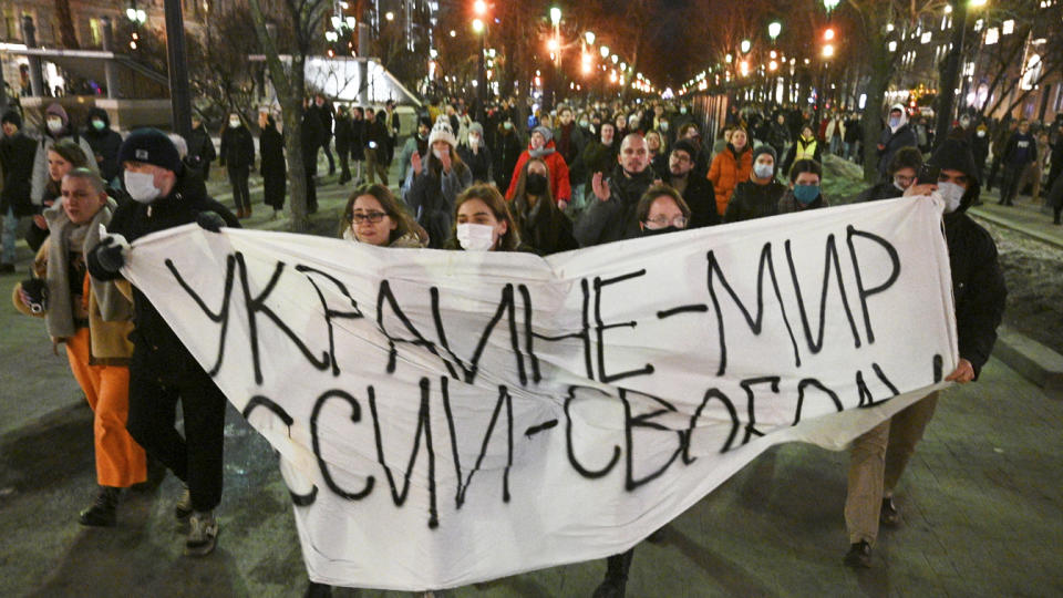 Young demonstrators march with a makeshift banner that reads, in Russian: Ukraine — peace, Russia — freedom.
