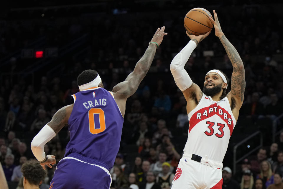 Toronto Raptors guard Gary Trent Jr. (33) looks to shoot over Phoenix Suns forward Torrey Craig (0) during the first half of an NBA basketball game, Monday, Jan. 30, 2023, in Phoenix. (AP Photo/Rick Scuteri)