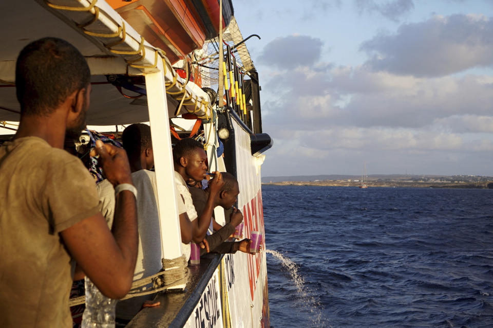 Migrants stand aboard the Open Arms Spanish humanitarian boat as it arrives near Lampedusa coast in the Mediterranean Sea, Thursday, Aug.15, 2019. A Spanish aid boat with 147 rescued migrants aboard is anchored off a southern Italian island as Italy's ministers spar over their fate. (AP Photo/Francisco Gentico)