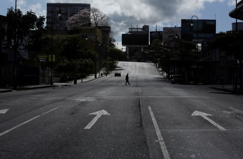 FILE PHOTO: A man walks in a virtually empty street of the capital, after prevention measures were announced by the health and government authorities due to the coronavirus disease (COVID-19), in San Jose