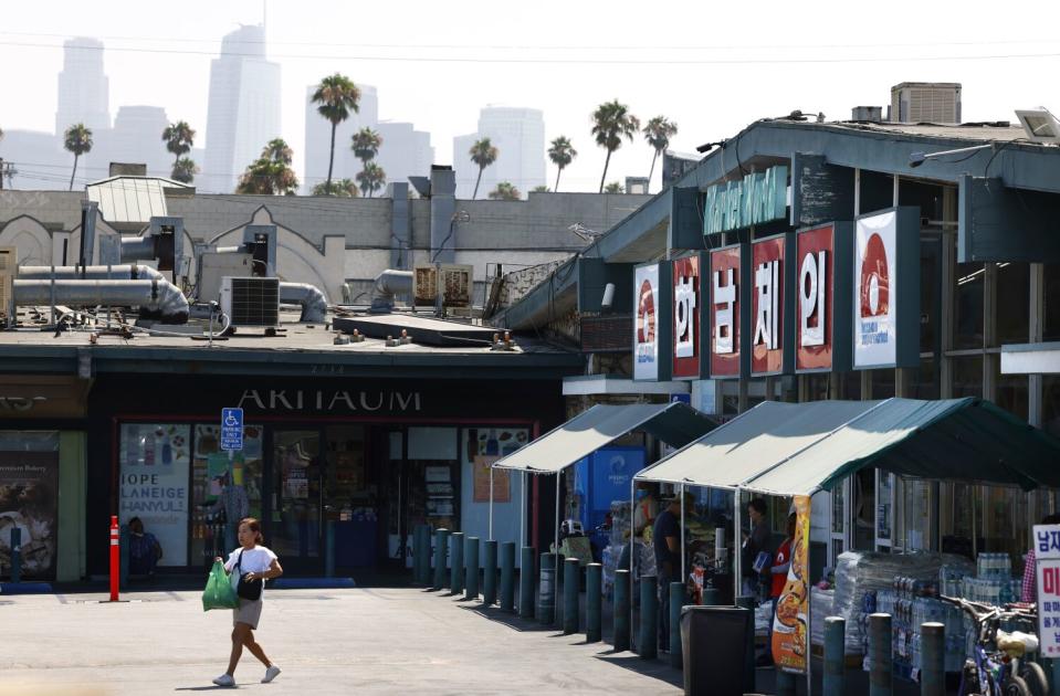 A cluster of single-story buildings with the downtown L.A. skyline and palm trees on the horizon