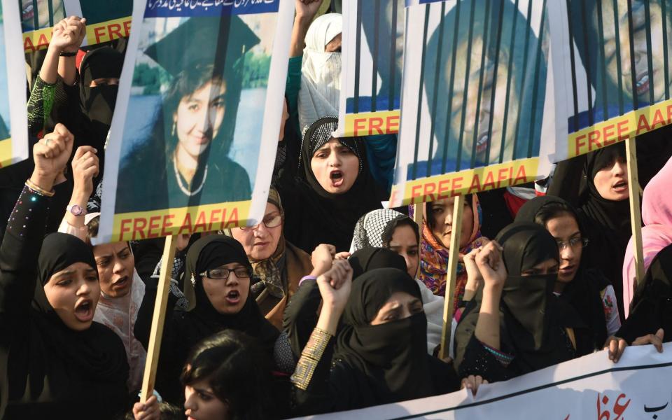 Pakistani protesters carry portraits of Siddiqui as they stage a demonstration for her release in Lahore in 2014 - AFP