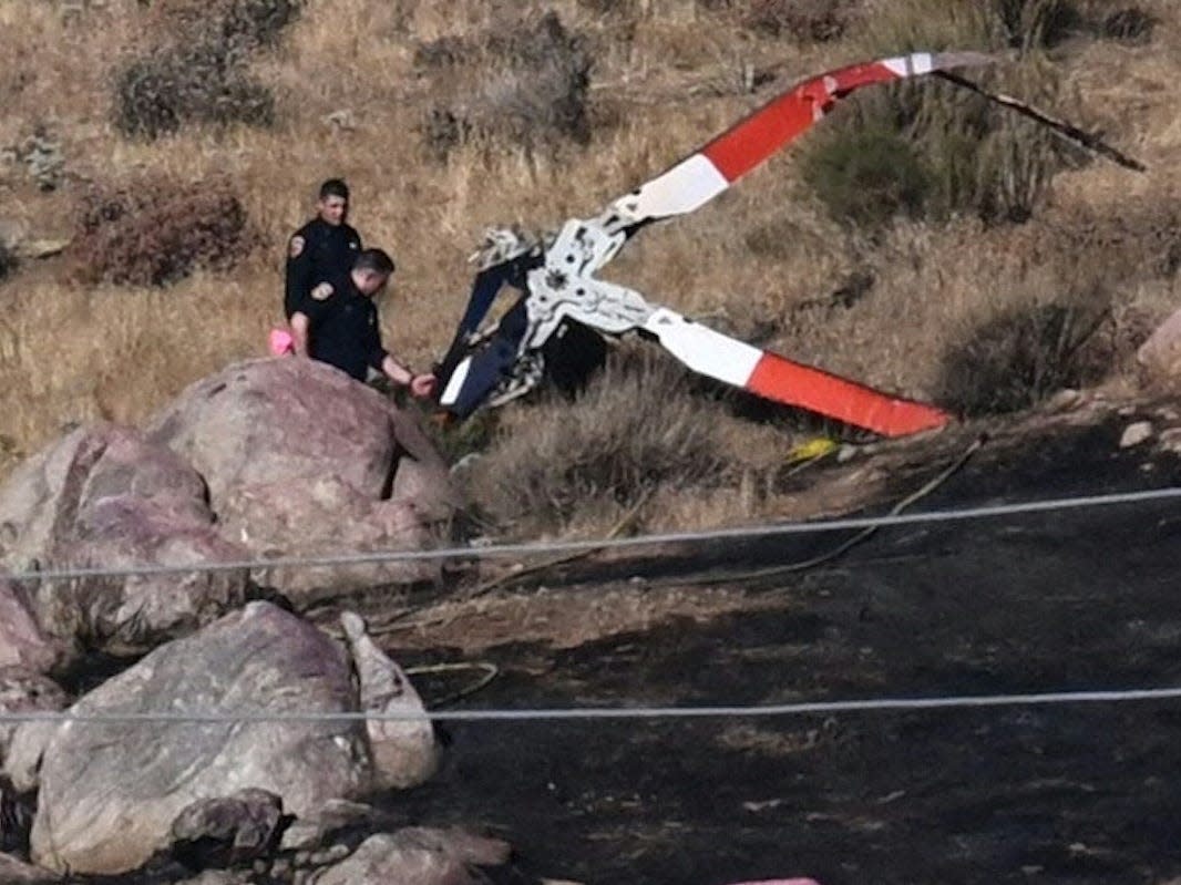 Investigators walk around rotor blades from one of the crashed helicopters on a burned hillside in Cabazon, California.