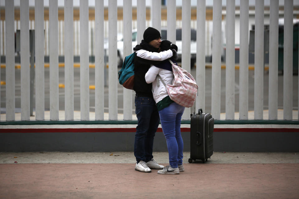 FILE - In this Dec. 21, 2018 file photo, migrants embrace after receiving one of the fifty turns for an interview to request U.S. asylum, alongside the El Chaparral pedestrian border crossing in Tijuana, Mexico. The Mexican government said Friday, Jan. 25, 2019 that the United States plans to return 20 migrants per day to Mexico as they await an answer to their U.S. asylum claims. The spokesman for Mexico's Foreign Relations Department says Mexico doesn't agree with the move, but will accept the migrants at the San Ysidro border crossing, near Tijuana. (AP Photo/Moises Castillo, File)