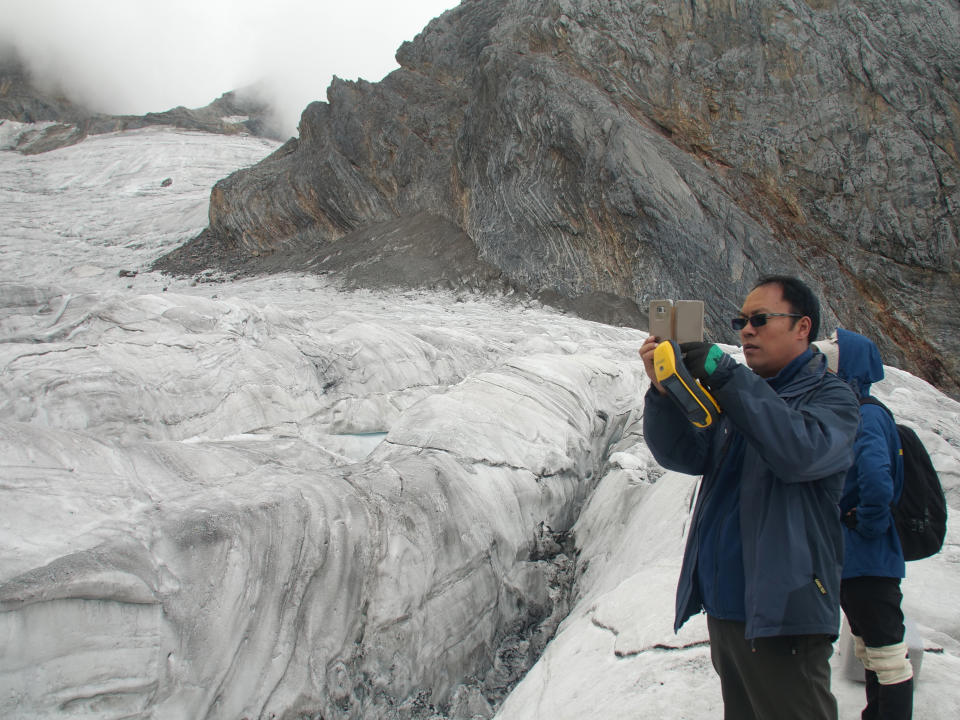 This Sept. 22, 2018 photo shows glaciologist Wang Shijin photographing the Baishui Glacier No.1 on the Jade Dragon Snow Mountain in the southern province of Yunnan in China. Scientists say the glacier is one of the fastest melting glaciers in the world due to climate change and its relative proximity to the Equator. It has lost 60 percent of its mass and shrunk 250 meters since 1982. (AP Photo/Sam McNeil)