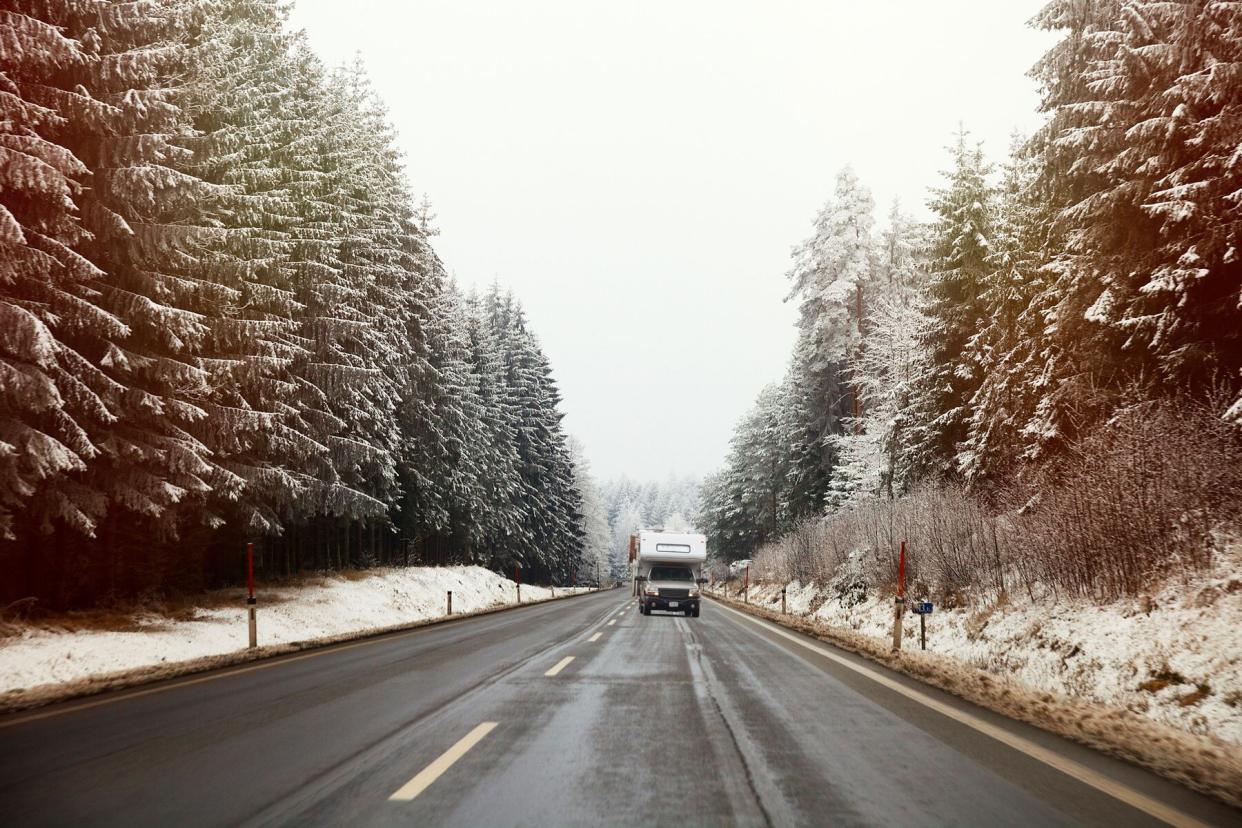 RV on snowy road with evergreen trees
