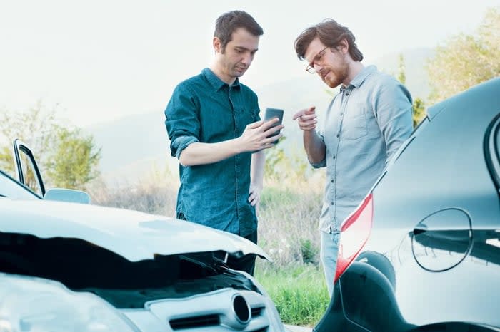 One Driver Taking Picture With Phone Of Car Accident While Other Driver Points At Phone.