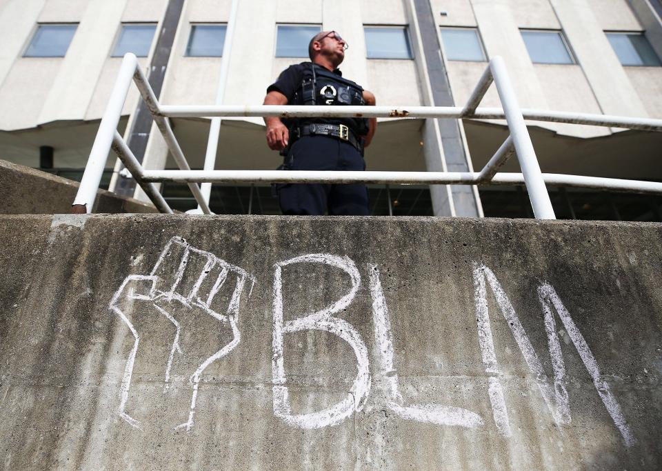 An Akron police officer watches as protesters gather Saturday outside the Stubbs Justice Center in downtown Akron.