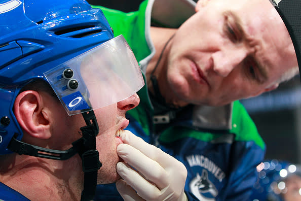 VANCOUVER, BC - JANUARY 17: Vancouver Canucks trainer Jon Sanderson checks the tooth of Alexandre Burrows #14 of the Vancouver Canucks during their NHL game against the Nashville Predators at Rogers Arena January 17, 2017 in Vancouver, British Columbia, Canada. Vancouver won 1-0. (Photo by Jeff Vinnick/NHLI via Getty Images)