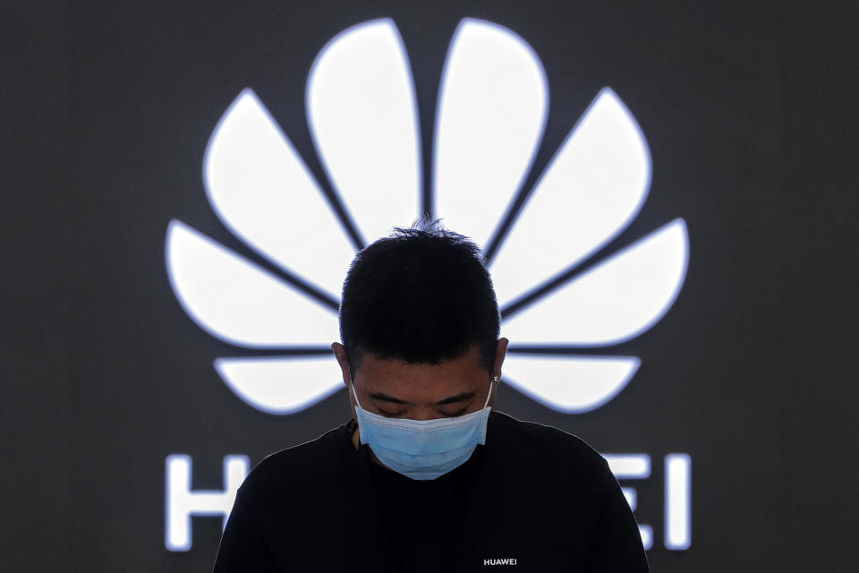 FILE - In this Aug. 31, 2020, file photo, an employee wearing a face mask to help curb the spread of the coronavirus stands inside a Huawei flagship store in Beijing. Chinese tech giant Huawei said Wednesday, March 31, 2021, it eked out a gain in sales and profit last year but growth plunged after its smartphone unit was hammered by U.S. sanctions imposed in a fight with Beijing over technology and security.(AP Photo/Andy Wong, File)