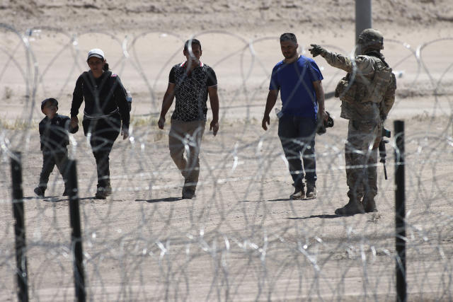 FILE - Migrants wait for U.S. authorities, between a barbed-wire barrier and the border fence at the US-Mexico border, as seen from Ciudad Juarez, Mexico, Wednesday, May 10, 2023. The U.S. on May 11 began to deny asylum to migrants who show up at the U.S.-Mexico border without first applying online or seeking protection in a country they passed through, according to a new rule released May 10. (AP Photo/Christian Chavez, File)