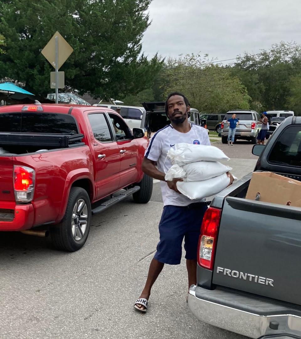 Ken Knight Drive resident Tyrone Harden lugs sandbags being delivered to help the Northside Jacksonville neighborhood prepare for Hurricane Ian's effects.