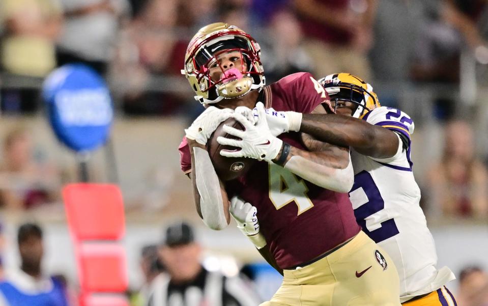Keon Coleman of the Florida State Seminoles catches a pass against Duce Chestnut of the LSU Tigers.