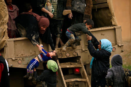 Displaced Iraqi women who fled their homes during a battle between Iraqi forces and Islamic State militants, try to get out of a vehicle with their children at a checkpoint, to be transfer to Hammam al-Alil camp, in Mosul. REUTERS/Thaier Al-Sudani