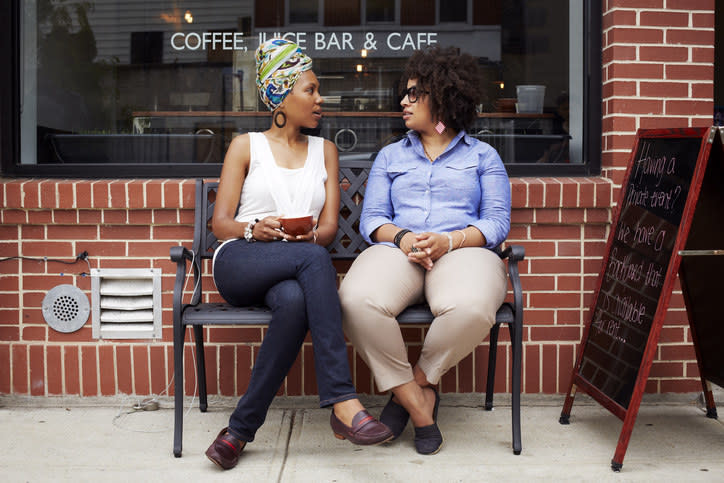 Two women sitting on a bench outside a café