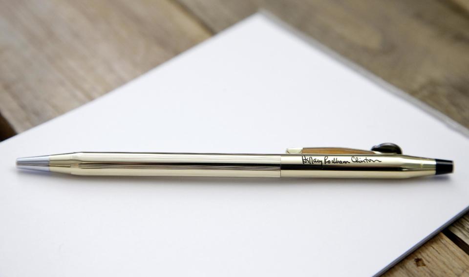 In this Tuesday, Feb. 14, 2017, photo an A.T. Cross Co., custom-made Cross Classic Century gold pen, featuring the signature of Hillary Clinton, and designed as a inaugural commemorative, rests on a paper tablet at the Cross Company Store in Providence, R.I. Andy Boss, of A.T. Cross Co., said a supplier to the Democratic National Committee initiated production of the the pens, though fewer than a dozen were produced by Cross. (AP Photo/Steven Senne)