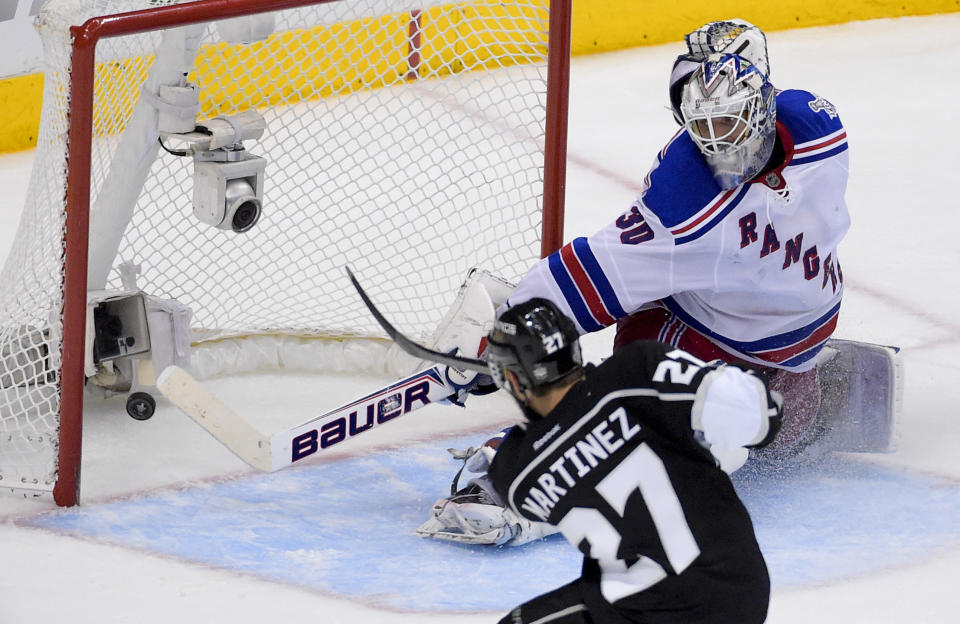 Los Angeles Kings defenseman Alec Martinez, left, scores the winning goal past New York Rangers goalie Henrik Lundqvist, of Sweden, during the second overtime period in Game 5 of an NHL hockey Stanley Cup finals, Friday, June 13, 2014, in Los Angeles.  (AP Photo/Mark J. Terrill)