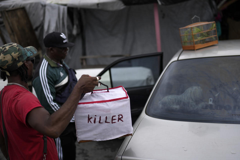 A man holds the cage of a winning songbird called Killer at the Stabroek Market in Georgetown, Guyana, Saturday, April 22, 2023. Killer's owner, Steve Skete, back, has won several competitions, earning himself a name in the Guyanese centuries-old songbirds tradition. (AP Photo/Matias Delacroix)