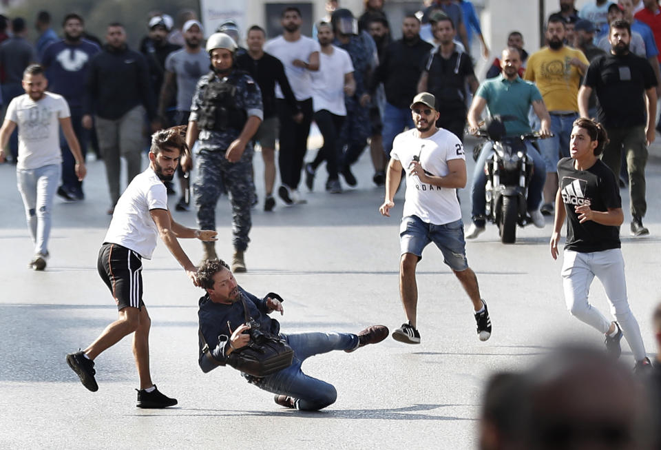 A French photographer is attacked by Hezbollah supporters while covering clashes between them and anti-government protesters, in Beirut, Lebanon, Tuesday, Oct. 29, 2019. The violence came shortly after dozen others, wielding sticks, attacked a roadblock on a main Beirut thoroughfare set up by the protesters. (AP Photo/Hussein Malla)