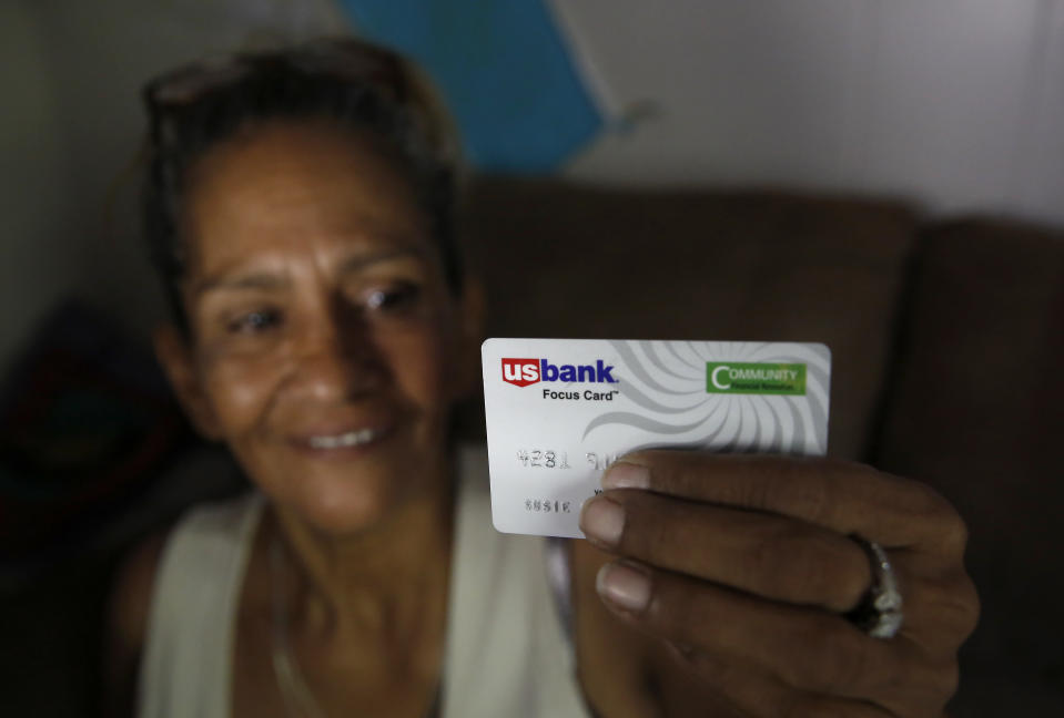 In this photo taken Wednesday, Aug. 14, 2019, Susie Garza displays the city provided debit card she receives monthly through a trial program in Stockton, Calif. Garza is participating in the Stockton Economic Empowerment Demonstration. The program, which started in February, gives $500 a month to 125 people who earn at or below the median household income of $46,033. They can spend the money with no restrictions. Stockton Mayor Michael Tubbs, who initiated the privately funded program, says it could be a solution to the city's poverty problem. (AP Photo/Rich Pedroncelli)