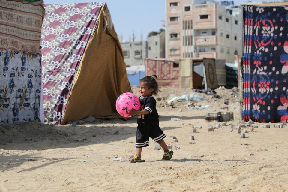 A Palestinian child plays with a ball amid tents at an area housing internally displaced people, in Nuseirat in the central Gaza Strip on Friday (AFP via Getty Images)