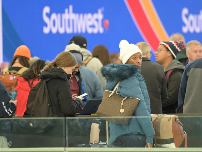 Canceled flight travelers line for booking in front of a Southwest Airlines sign at Denver International Airport in Denver, Colorado