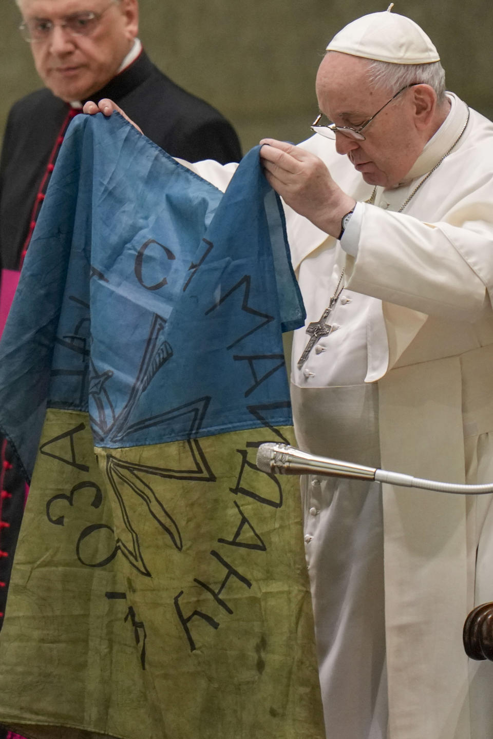 Pope Francis shows a flag that was brought to him from Bucha, Ukraine, during his weekly general audience in the Paul VI Hall, at the Vatican, Wednesday, April 6, 2022. (AP Photo/Alessandra Tarantino)