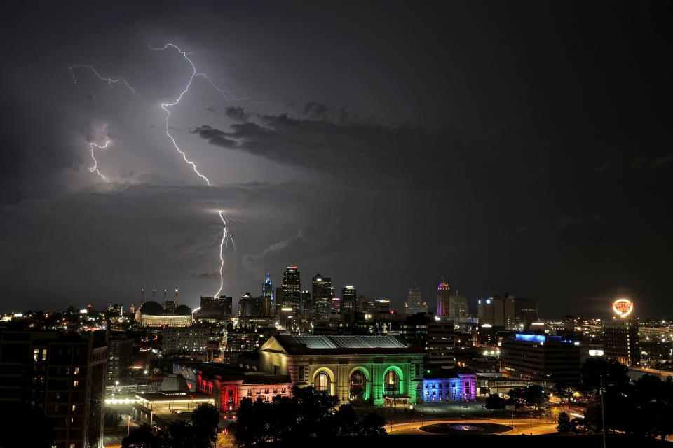 Lightning flashes beyond downtown buildings as a thunderstorm passes in the distance Saturday, June 11, 2022, in Kansas City, Mo. (AP Photo/Charlie Riedel)