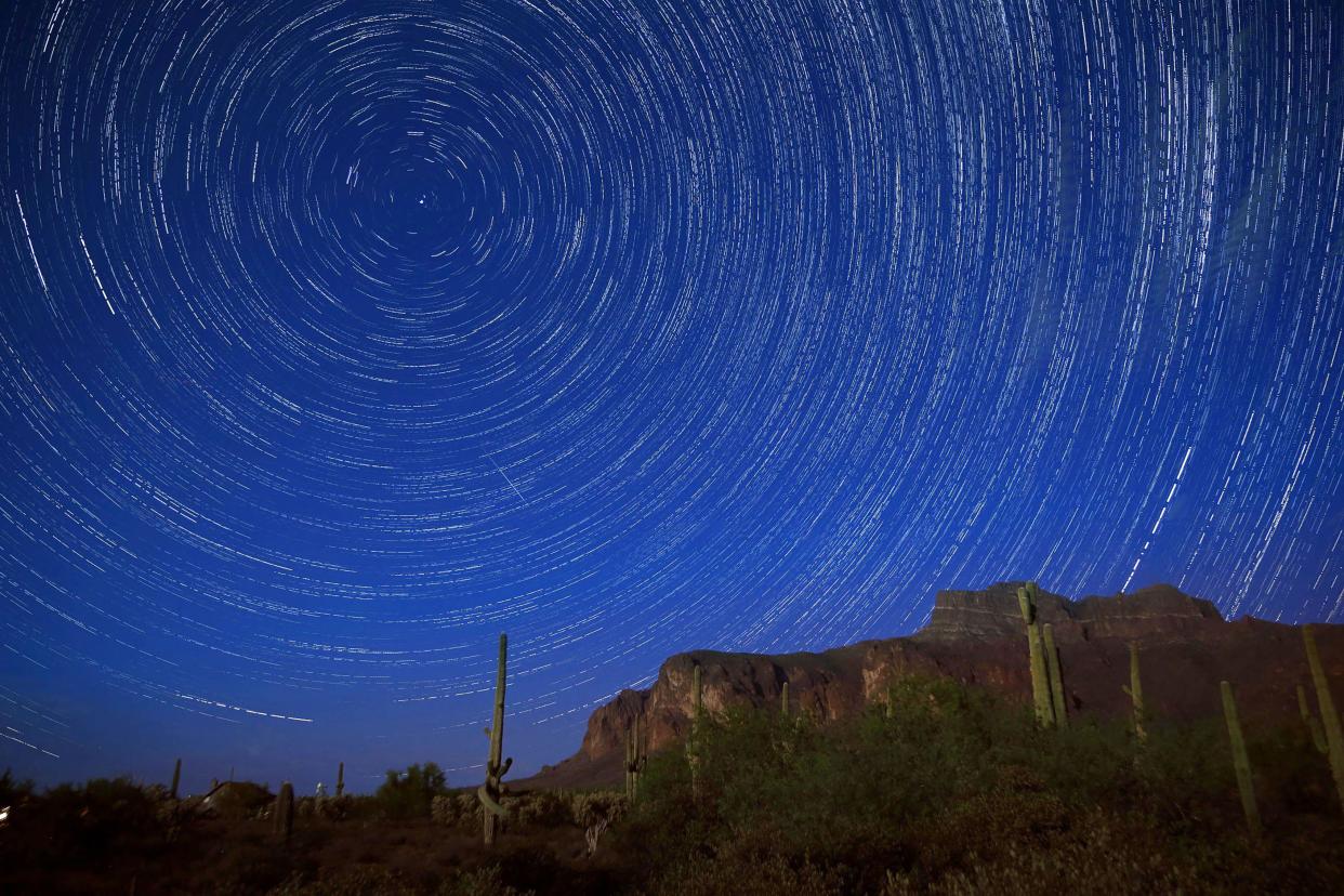 Star trails and a meteor from the Perseid meteor shower can be seen beyond the Superstition Mountains in Arizona in 2016.