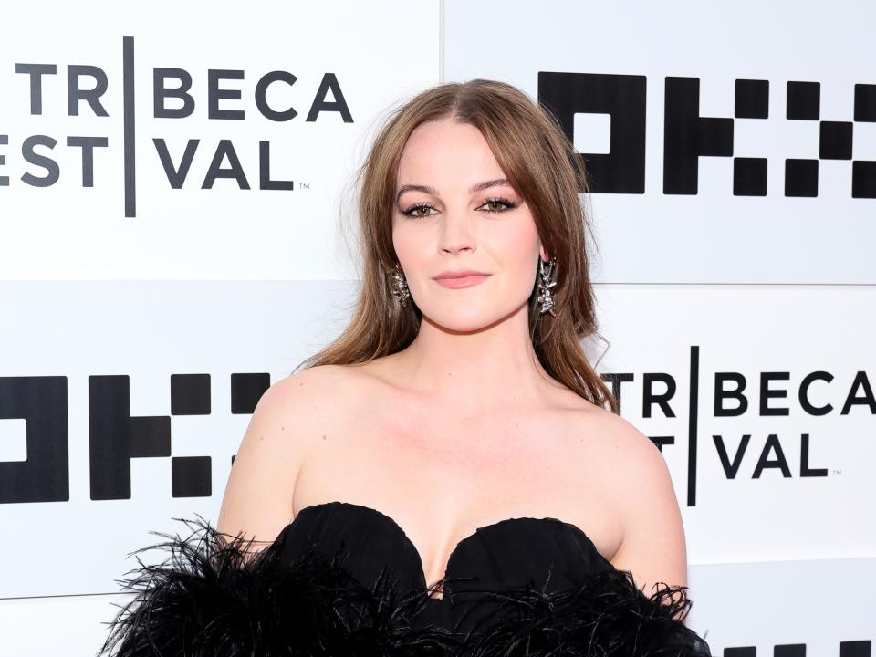 Izzy Meikle-Small wearing a feathered, strapless black dress and large silver earrings.