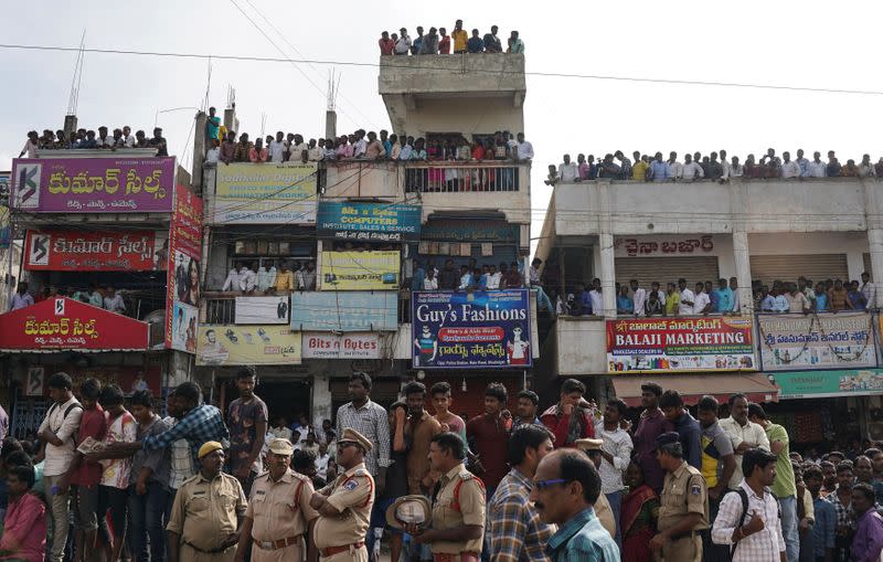Police officers stand guard as people attend a protest against the alleged rape and murder of a 27-year-old woman in Shadnagar