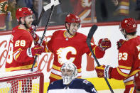 Calgary Flames' Elias Lindholm, left, celebrates his goal against the Winnipeg Jets with Johnny Gaudreau, center, and Sean Monahan during the first period of an NHL hockey game Saturday, Nov. 27, 2021, in Calgary, Alberta. (Larry MacDougal/The Canadian Press via AP)