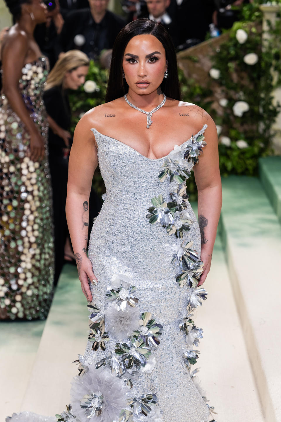 Demi Lovato in a sparkling strapless silver gown with floral accents at the Met Gala